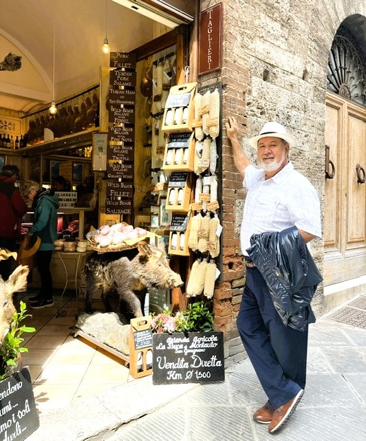 Shopkeeper displaying pasta outside Italian store San Gimignano