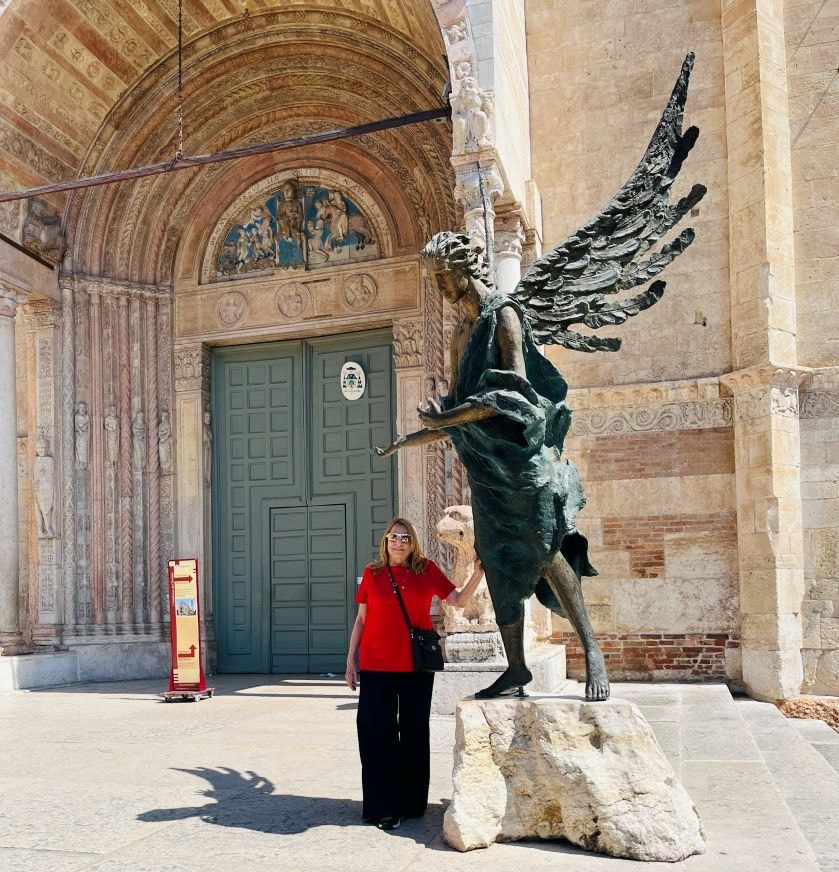 Daren posing with winged statue at Verona cathedral entrance